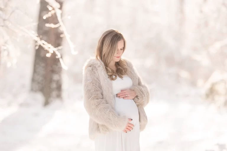 A pregnant woman in the snow posing for her maternity photoshoot