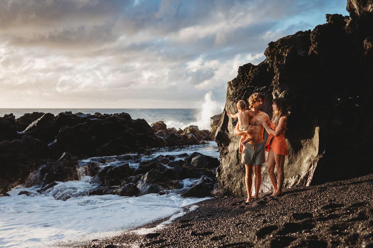 Photo of a mom, dad and their toddler on a black sand beach in Hawaii for a family session