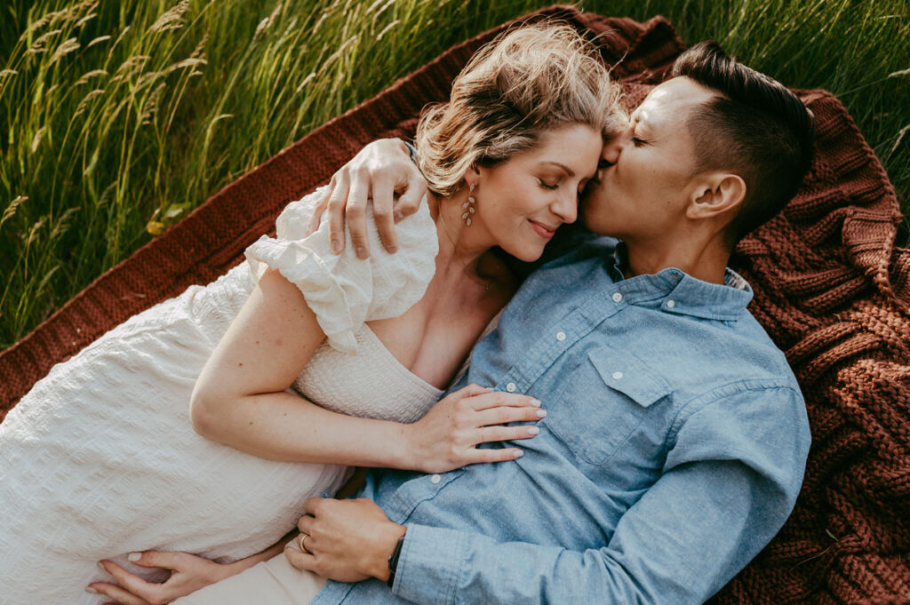 Couple snuggling on a blanket for a maternity photoshoot in Hingham, MA just south of Boston, MA