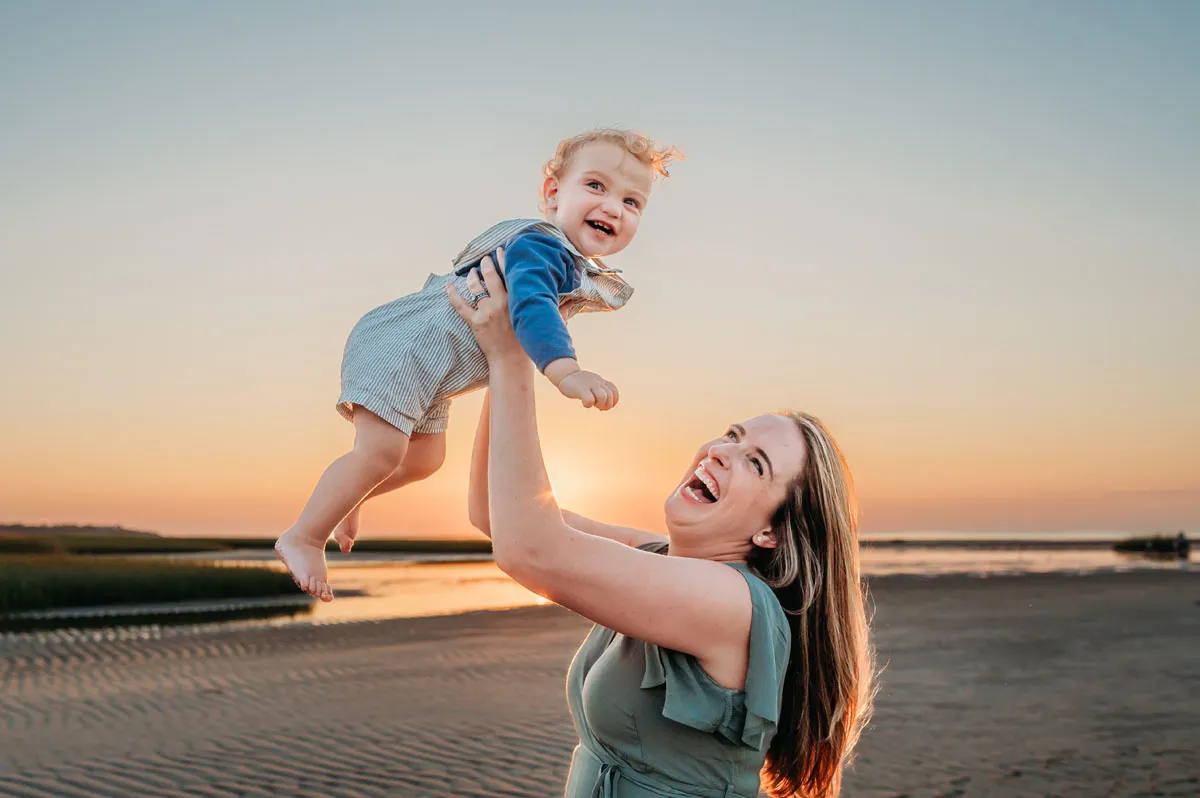 Caryn Scanlan Cape Cod Photographer mom swinging her son in the air on the beach at Sunset