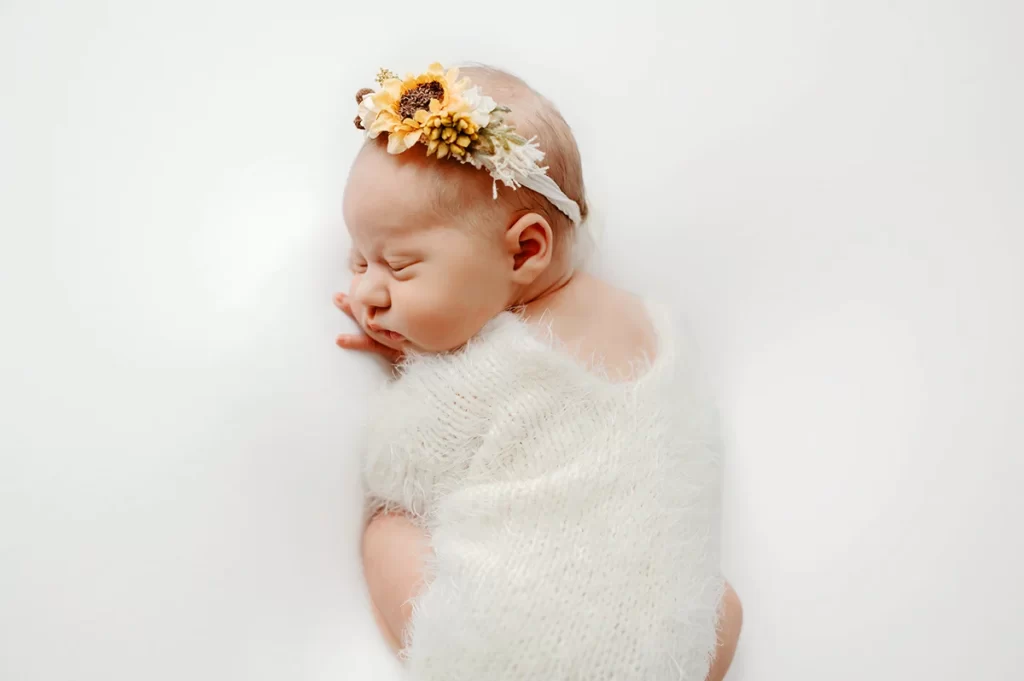 Plymouth Newborn photographer studio posed newborn with sunflower headband on white by Caryn Scanlan