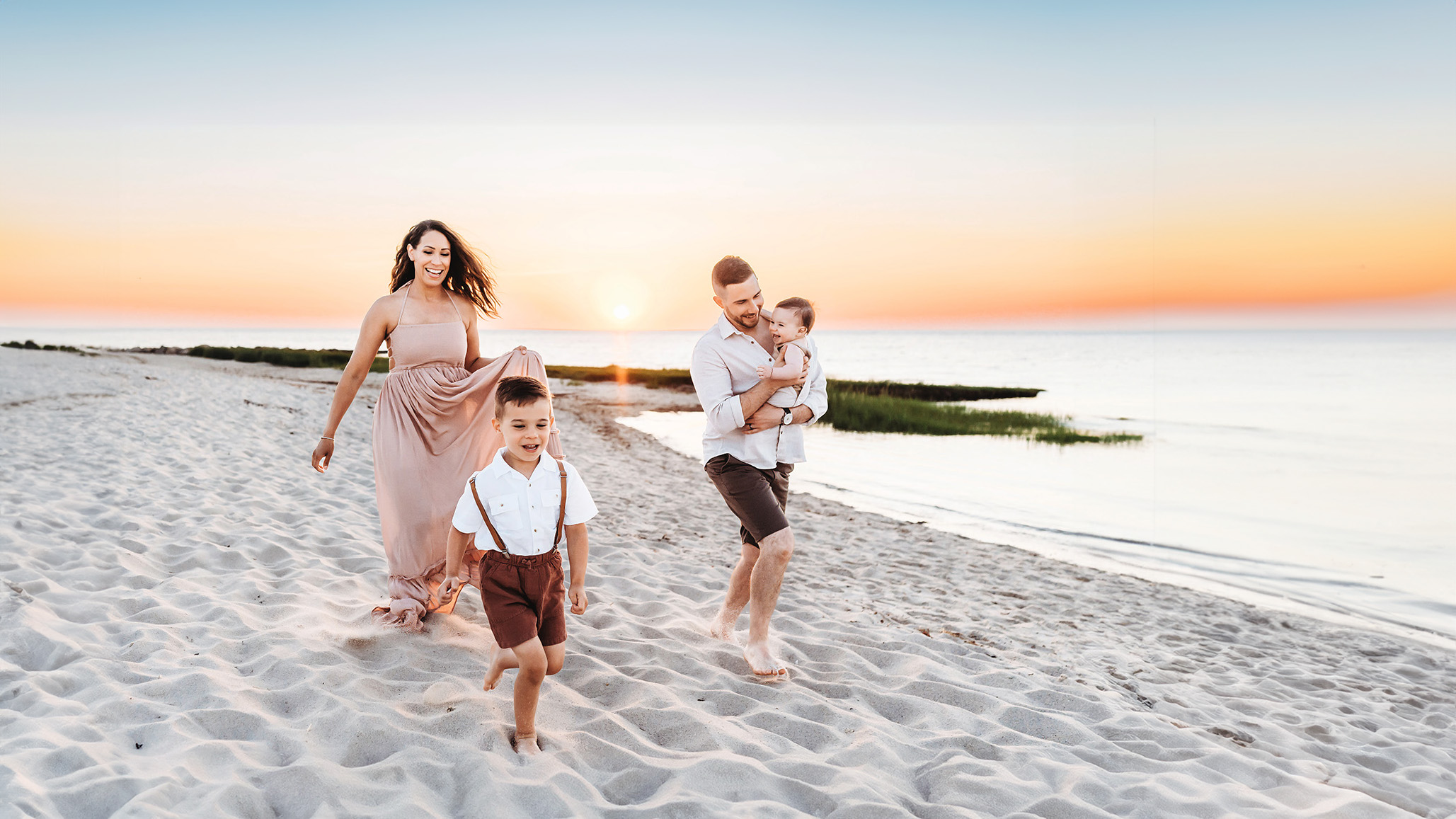 A happy family running along the beach in Brewster, Cape Cod at Sunset for their family photoshoot