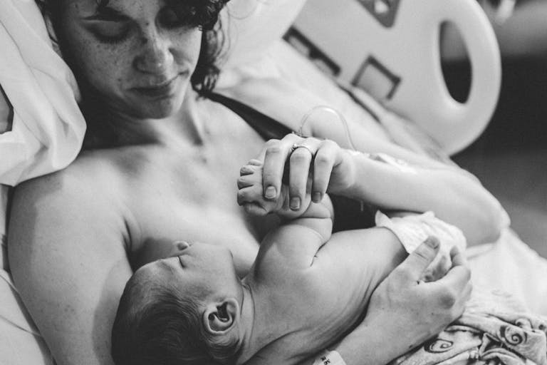 Monochrome Photograph of a Woman Carrying an Infant